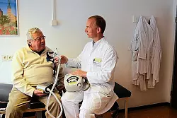 Horst Eikert freut sich, dass sein neues Atemger&auml;t so viel kleiner und leichter ist als das Vorg&auml;ngermodell, das Privatdozent Dr. Olaf Oldenburg &ndash; zusammen mit der Atemmaske &ndash; festh&auml;lt. - &copy; FOTO: H. FROREICH
