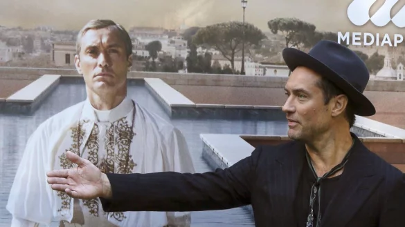 Jude Law vor einem Plakat mit sich als Papst Pius XIII. in der Serie &laquo;The Young Pope&raquo;. (Archivbild) - &copy; picture alliance / dpa
