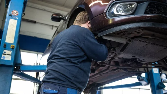 Ein Mechaniker schaut in einer Kfz-Werkstatt in den Radkasten eines Autos. - © Hannes P. Albert/dpa