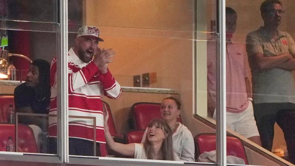 Er jubelt, sie wirft ihm einen verliebten Blick zu: Travis Kelce und Taylor Swift bei einem College-Football-Spiel. - © Charlie Riedel/AP/dpa