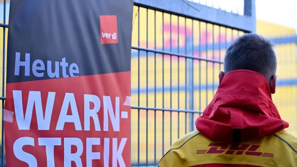 Streikposten am Werkstor: Ein DHL-Mitarbeiter hat die Arbeit niedergelegt und schaut auf eine Zustellbasis, in der er sonst arbeitet. - © Wolf von Dewitz/dpa