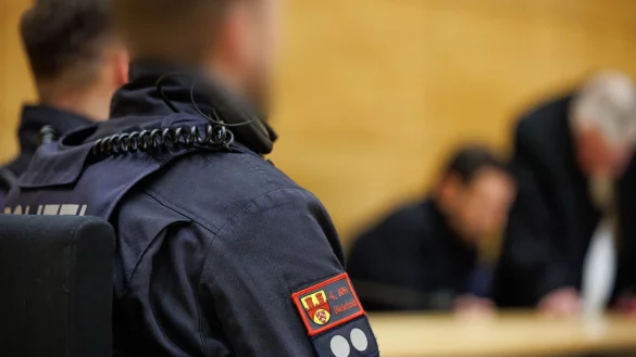 Polizisten sitzen neben dem Angeklagten (hinten) in einem Saal vom Landgericht Bielefeld bei der Fortsetzung des Prozesses um den Mord an einem Profiboxer. - © Friso Gentsch/dpa