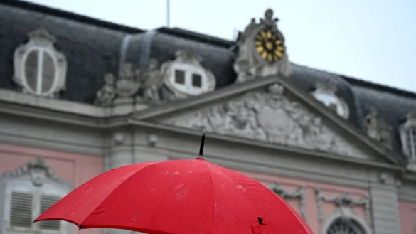 Eine Frau geht mit ihrem Regenschirm bei Regen am Schloss Benrath vorbei. - &copy; Wolf von Dewitz/dpa