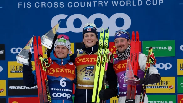 Johannes Hoesflot Klaebo (M) aus Norwegen jubelt neben dem Zweitplatzierten Mika Vermeulen (l) aus Österreich und dem Drittplatzierten Hugo Lapalus aus Frankreich auf dem Podium der Tour de Ski. - © Alessandro Trovati/AP/dpa