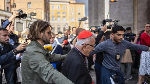 Auf dem Weg zum Vatikan kämpfen sich die Kardinäle durch eine Menge aus Journalisten und Schaulustigen. - © Oliver Weiken/dpa