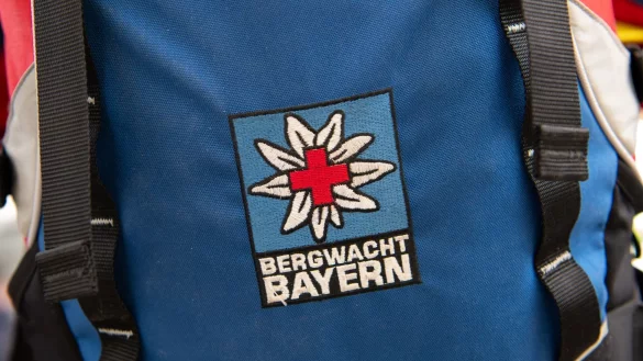 Das Logo der Bergwacht ist an einem Rucksack zu sehen. Bei Oberstdorf musste die Bergwacht nun einen Mann retten, der ohne richtige Ausr&uuml;stung und Erfahrung zwei N&auml;chte in den Bergen verbrachte. (Archivfoto-Illustration) - &copy; Sven Hoppe/dpa