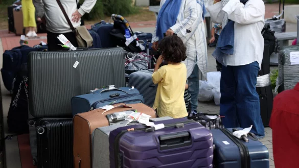 Menschen aus Afghanistan, die zuvor mit einem Flugzeug am Flughafen Hannover gelandet sind, stehen im Grenzdurchgangslager Friedland an ihren Koffern. - © Stefan Rampfel/dpa