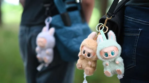 Zwei Frauen tragen Labubu-Anhänger an ihren Umhängetaschen. (Archivbild) - © Lars Penning/dpa
