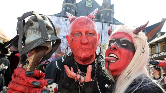 Im Teufelskostüm stehen Besucher auf dem Marktplatz in Wernigerode. - © Matthias Bein/dpa