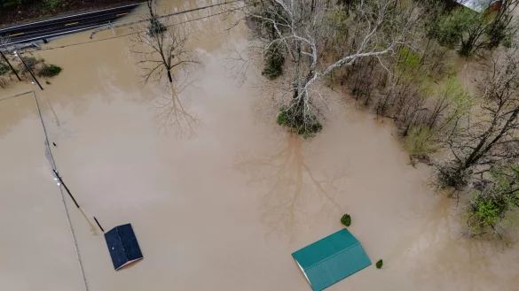Die braune Brühe ließ Häuser und Autos bis zur Dachkante versinken - oder spülte sie komplett fort. - © Jon Cherry/AP/dpa