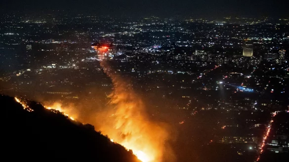 Die Löscharbeiten in den berühmten Hollywood Hills dauern an, die Behörden geben aber leichte Entwarnung. - © Ethan Swope/AP/dpa