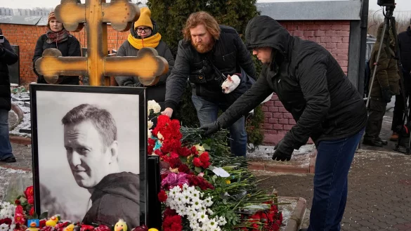 Menschen legen ein Jahr nach dem Tod des russischen Oppositionsführers Alexej Nawalny auf dem Borisowskoje-Friedhof in Moskau Blumen an seinem Grab nieder. - © Uncredited/AP/dpa