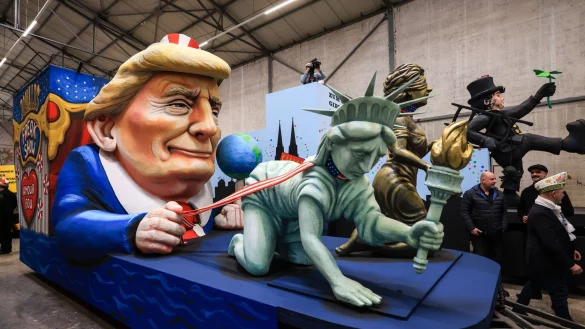 Einer der Wagen im Kölner Rosenmontagszug zeigt US-Präsident Donald Trump, der die Freiheitsstatue und die Justitia am Laufband führt. - © Oliver Berg/dpa