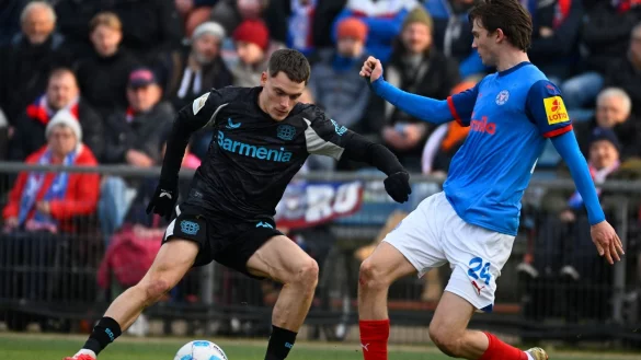 Leverkusens Florian Wirtz (l) wurde von Kiels Magnus Knudsen in einer anderen Szene böse gefoult. - © Gregor Fischer/dpa