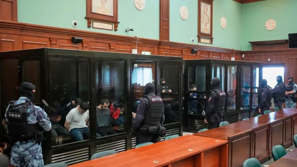 Die 19 Angeklagten saßen schwer bewacht in gläsernen Käfigen. - © Pavel Bednyakov/AP/dpa