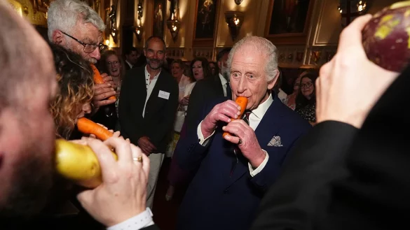 König Charles III. versuchte sich an der Karottenflöte. - © Aaron Chown/PA Pool/AP/dpa