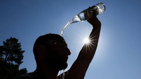 Ein Mann kühlt sich bei Hitze ab. (Archivbild) - © Thomas Warnack/dpa