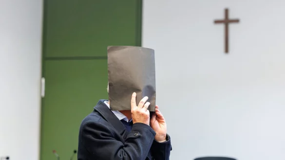 Der Angeklagte versteckte zu Prozessbeginn sein Gesicht. Er bestreitet die Vorwürfe. - © Matthias Balk/dpa