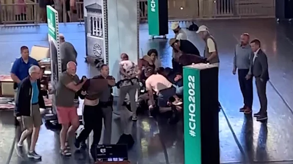 Menschen k&uuml;mmern sich um den verletzten Rushdie, w&auml;hrend ein Mann von der B&uuml;hne eskortiert wird. (Aufnahme kurz nach dem Angriff) - &copy; Uncredited/AP/dpa