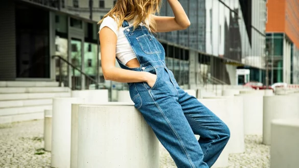 Besonders sportlich sieht die Latzhose in Kombination mit weißem T-Shirt und angesagten Retro-Sneakern aus. Wer etwas Haut zeigen möchte, wählt ein Crop-Top. - © Christin Klose/dpa-tmn