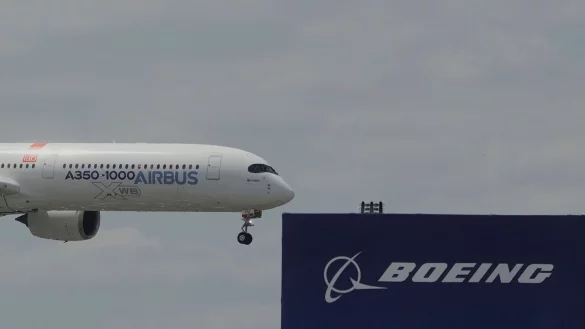 Die zwei gro&szlig;en Konkurrenten: Ein Airbus fliegt bei einer Vorf&uuml;hrung auf der Luftfahrtmesse Salon du Bourget an einem Logo von Boeing vorbei. - &copy; Michel Euler/AP/dpa