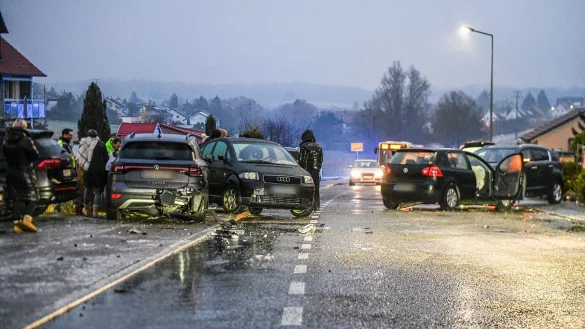 Nach einem Unfall bei Glatteis mit mehreren Fahrzeugen in Baden-Württemberg stehen Helfer und Beteiligte an den Autos auf einer Straße. - © Jason Tschepljakow/dpa