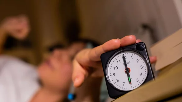 Eine Frau schaltet vom Bett aus einen auf sechs Uhr gestellten Wecker aus. - &copy; Christoph Soeder/dpa