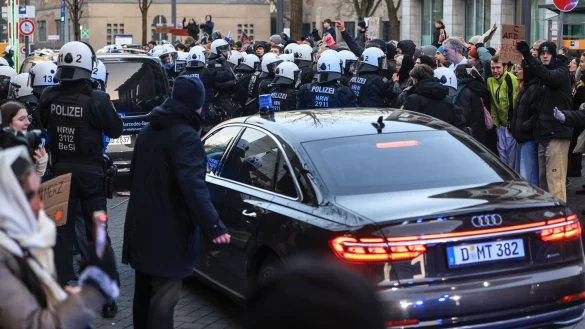 Polizisten schieben Demonstranten beiseite, damit Autos das Gel&auml;nder der K&ouml;lner Uni-Klinik verlassen k&ouml;nnen. - &copy; Oliver Berg/dpa