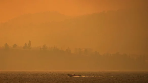 Ein Boot fährt auf dem Okanagan-See, während der Rauch des McDougall-Creek-Wildfeuers über dem Gebiet liegt. - © Darryl Dyck/The Canadian Press via AP/dpa