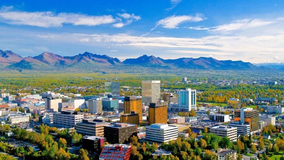 Skyline in gr&uuml;ner Weite mit Bergen am Horizont: Anchorage ist die gr&ouml;&szlig;te Stadt in Alaska. - &copy; Frank P. Flavin/Visit Anchorage/dpa-tmn