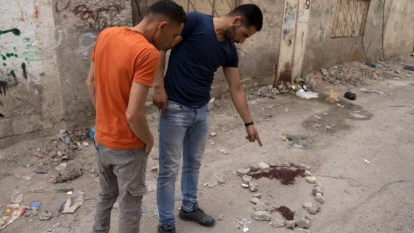 Palästinenser zeigen auf einen Blutfleck auf dem Boden. - © Nasser Nasser/AP/dpa