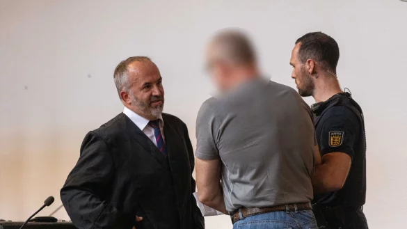 Der Angeklagte (M) spricht mit seinem Verteidiger (l) im Gericht. - © Philipp von Ditfurth/dpa