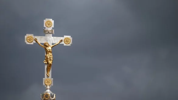 Ein katholisches Kruzifix ist vor dunklen Wolken zu sehen. - &copy; Marijan Murat/dpa/Symbolbild