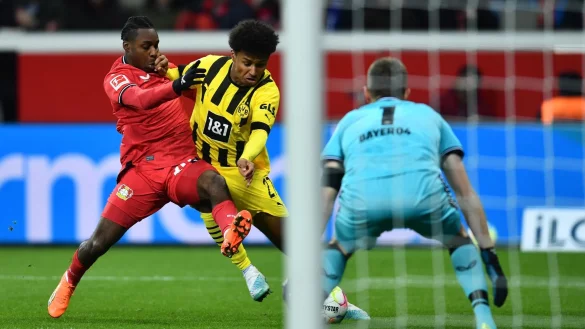 Dortmunds Karim Adeyemi (M) und Leverkusens Jeremie Frimpong k&auml;mpfen um den Ball. - &copy; Marius Becker/dpa