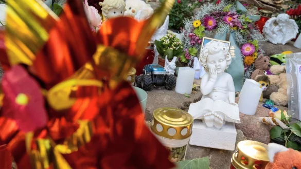 Neben einem Fußballfeld an einem See in Pragsdorf, dem möglichen Tatort, sind Kerzen, Plüschtiere und Fotos abgelegt. - © Stefan Sauer/dpa