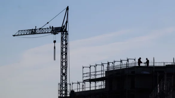 Bauarbeiter stehen auf der Baustelle eines Mehrfamilienhauses. - &copy; Julian Stratenschulte/dpa/Symbolbild