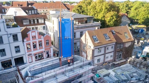 Ein tonnenschweres Scheibenteil wird von einem Kran in das im Umbau befindlche Meeresmuseum manövriert. - © Stefan Sauer/dpa