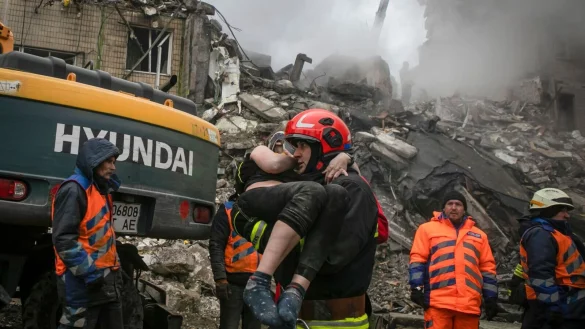 Nach dem Einschlag einer russischen Rakete in Dnipro evakuieren Rettungskr&auml;fte eine verletzte Frau aus dem mehrst&ouml;ckigen Wohnhaus. - &copy; Yevhenii Zavhorodnii/AP/dpa