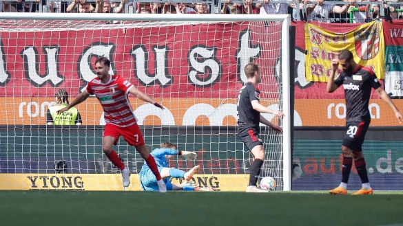 Augsburgs Dion Drena Beljo (l) jubelt nach seinem Tor zum 1:0, der Berliner Torwart Frederik R&ouml;nnow (M) schaut dem Ball im Netz nach. - &copy; Daniel L&ouml;b/dpa