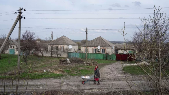 Eine Frau transportiert in Lyman im umk&auml;mpften Osten der Ukraine Hilfsg&uuml;ter auf einer Schubkarre. - &copy; Evgeniy Maloletka/AP