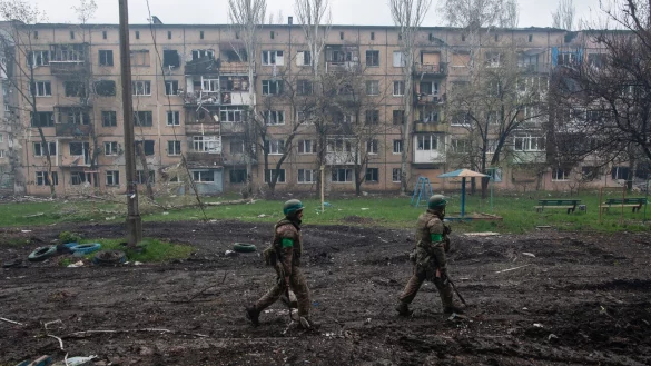 Ukrainische Soldaten gehen in Bachmut an stark beschädigten Gebäuden vorbei. - © Iryna Rybakova/AP/dpa
