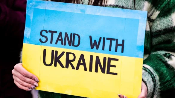 Der Schriftzug &laquo;Stand with Ukraine&raquo; ist auf dem Plakat einer Demonstrantin zu lesen. - &copy; Moritz Frankenberg/dpa/Archivbild