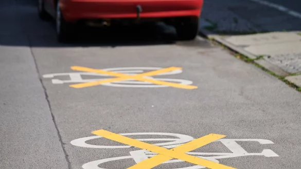 Auf der Ollenhauer Stra&szlig;e sind die Zeichen f&uuml;r den Radweg mit gelben Kreuzen zugeklebt und Autos parken darauf. Der Radweg existiert nicht mehr. - &copy; Annette Riedl/dpa