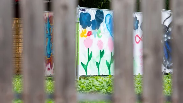 Am Rand einer Brachfl&auml;che h&auml;ngen von Kindern gestaltete Plakate an Bauz&auml;unen. An dieser Stelle stand das Haus, vor dem der Messerangriff auf zwei Sch&uuml;lerinnen stattfand. - &copy; Stefan Puchner/dpa
