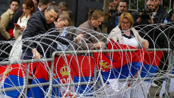 Frauen befestigen serbische Flaggen an einem Zaun vor dem Rathaus während einer Demonstration in der Stadt Zvecan im Norden des Kosovo. - © Bojan Slavkovic/AP