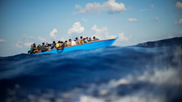 Migranten sitzen in einem Holzboot s&uuml;dlich der italienischen Insel Lampedusa auf dem Mittelmeer. - &copy; Francisco Seco/AP/dpa