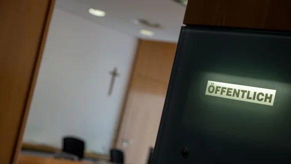 Eine Anzeigetafel weist an einem Sitzungssal auf eine öffentliche Verhandlung hin. - © Stefan Puchner/dpa/Symbolbild