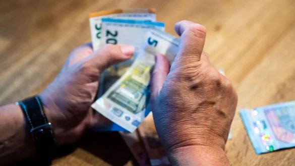 Ein &auml;lterer Mann z&auml;hlt Geld an einem Tisch. - &copy; Lino Mirgeler/dpa/Illustration