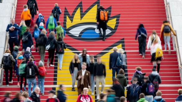 Viel Andrang: Besucherinnen und Besucher der Leipziger Buchmesse gehen zur Er&ouml;ffnung &uuml;ber eine Treppe mit dem Logo der Buchmesse. - &copy; Hendrik Schmidt/dpa
