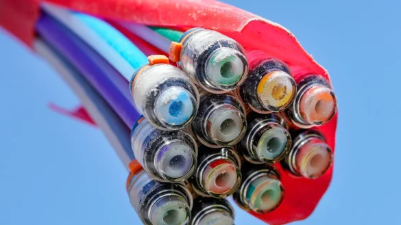 Ein B&uuml;ndel mit Umh&uuml;llungen f&uuml;r Glasfaserkabel h&auml;ngt vor einem blauen Himmel. - &copy; Uwe Anspach/dpa/Symbolbild
